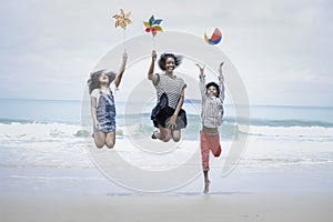 Cute groups of kids have fun on sandy summer beach with blue sea, happy childhood friends  jump together and play on tropical