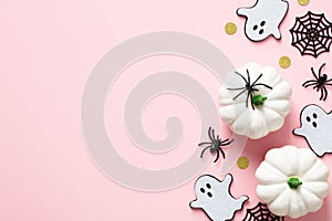 Cute Halloween decorations on pastel pink background. Flat lay ghosts, spiders, webs, white pumpkins. Halloween greeting card