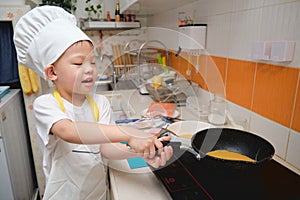 Cute happy Asian boy having fun cooking breakfast in kitchen, Fun indoor activities for kindergarten kids, Stay home Stay safe