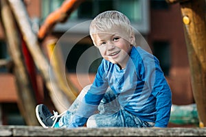 Cute happy baby boy with blond hair having fun on the playground