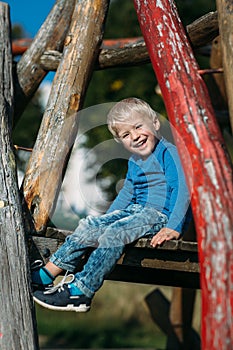 Cute happy baby boy with blond hair having fun on the playground