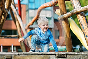 Cute happy baby boy with blond hair having fun on the playground