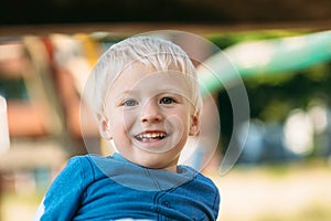 Cute happy baby boy with blond hair having fun on the playground