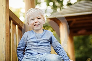 Cute happy baby boy with blond hair having fun on the playground