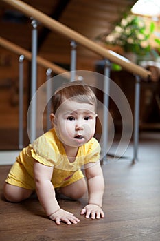 Cute happy baby boy crawling on the floor indoors, standing on knees