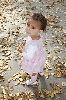 Cute happy baby girl among autumn leaves