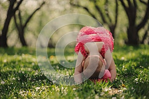 Cute happy baby girl in funny pink romper walking outdoor in spring garden