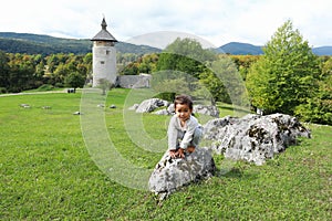 Cute happy boy climbing on rock in front of old town Dreznik