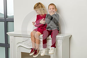 Cute Happy Boy and Girl Sitting Together on Mantelpiece
