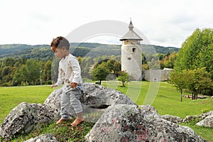 Cute happy boy standing on rocks in front of old town Dreznik