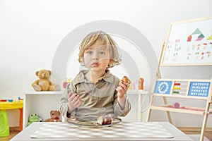 Cute happy child boy having fun eating chocolate cake at home. Chocolate, sweets and sugar, unhealthy food for children conceptual