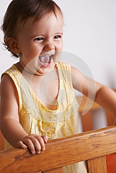 Cute, happy and a child in a crib for playing, wake up or comfort in a bedroom. Laughing, baby and a young kid in a