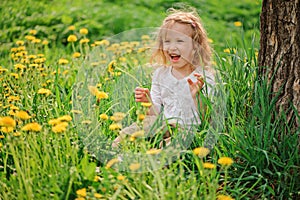 Cute happy child girl on dandelion flower field