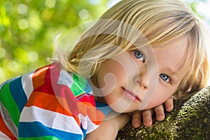 Cute, happy child relaxing deep in thought outdoors