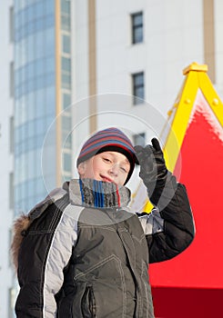 Cute happy child wearing warm winter jacket and a hat playing outdoors