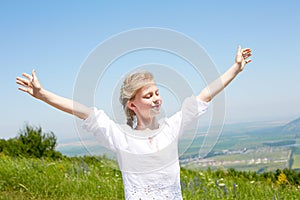 Cute happy child in white blouse on a rock with raised hands