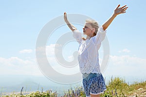 Cute happy child in white blouse on a rock with raised hands