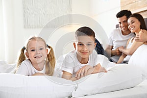 Cute happy children and their parents on bed