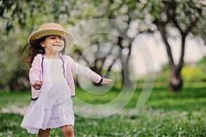 Cute happy dreamy toddler child girl walking in blooming spring garden, celebrating easter outdoor