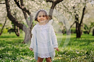 Cute happy dreamy toddler child girl walking in blooming spring garden, celebrating easter outdoor