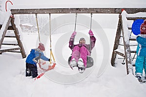Cute happy family, having fun on the playground, swinging in win