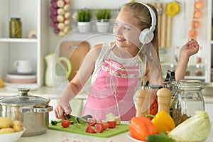 Cute happy girl coocking on kitchen and listening to music