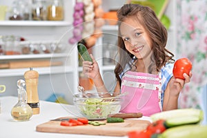 Cute happy girl coocking salad on kitchen