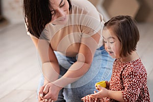 cute happy girl with down syndrome at home with mom playing with toys