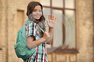 Cute happy girl with long hair in casual style carry travel bag waving goodbye hand gesture outdoors, wanderlust, copy