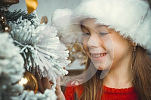 Cute happy girl in red hat hangs decorations