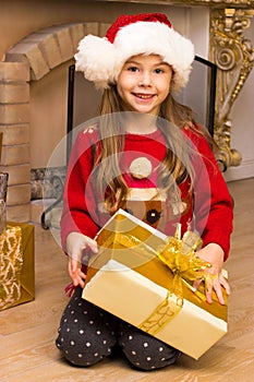 Cute happy girl in red hat holding present
