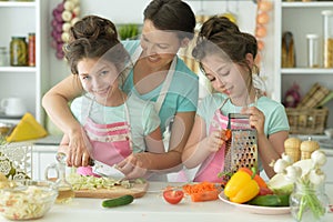 Cute happy girls coocking on kitchen with mother