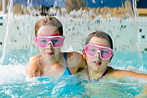 Cute happy girls in pink goggles mask in the swimming pool