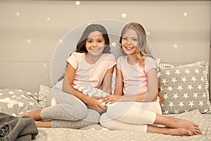 Always cute. Happy girls sit on bed. Beauty look of little girls. Small girls wear home clothing. International day of