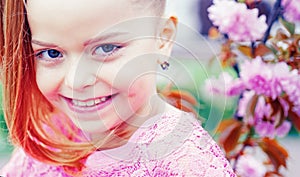 Cute happy joyful girl with long hair close up. Springtime. Childhood. Funny holliday. Cute child having fun on a sunny