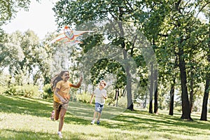 cute happy kids playing with colorful kite in park