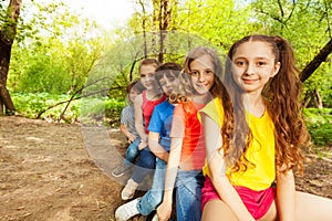 Cute happy kids sitting on a log in the forest