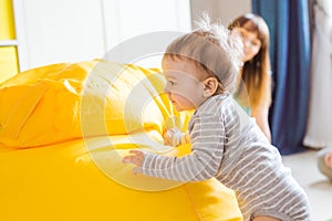 Cute happy laughing baby boy playing on white bedroom.