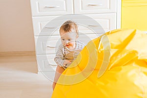 Cute happy laughing baby boy playing on white bedroom.