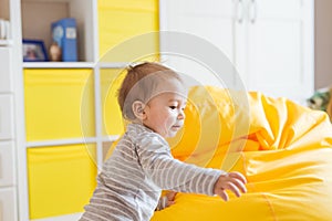 Cute happy laughing baby boy playing on white bedroom.