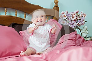 Cute happy laughing baby playing on bed.