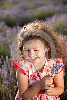 Beautiful happy laughing little girl with bouquet of flowers in lavender field