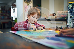 Cute happy little boy, adorable preschooler, painting in a sunny art studio. Young artist at work