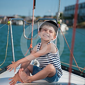 Cute happy little boy in captain`s cap travels on luxury boat