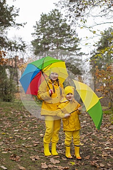 Cute happy little boy and a girl - brother and sister - in identical yellow costumes and hats walking in the forest with rainbow-