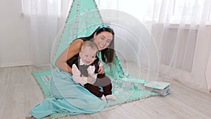 Cute happy little boy playing with his mother in the nursery.