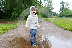Cute happy little boy in wellingtons walking after rain