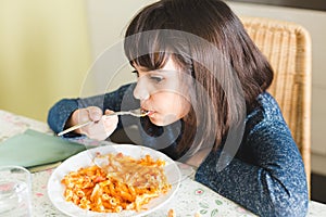 Little girl eating pasta with tomatoo sauce