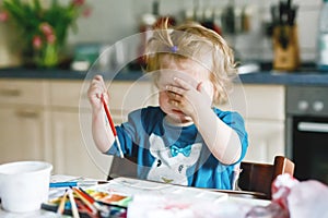Cute happy little girl painting with water color on paper. Baby child learning different skills, creative leisure and