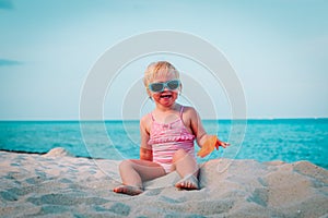 Cute happy little girl play with sand on beach